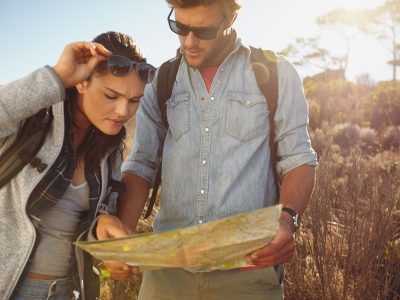 Hikers looking at map. Couple navigating together during travel hike outdoors in countryside.